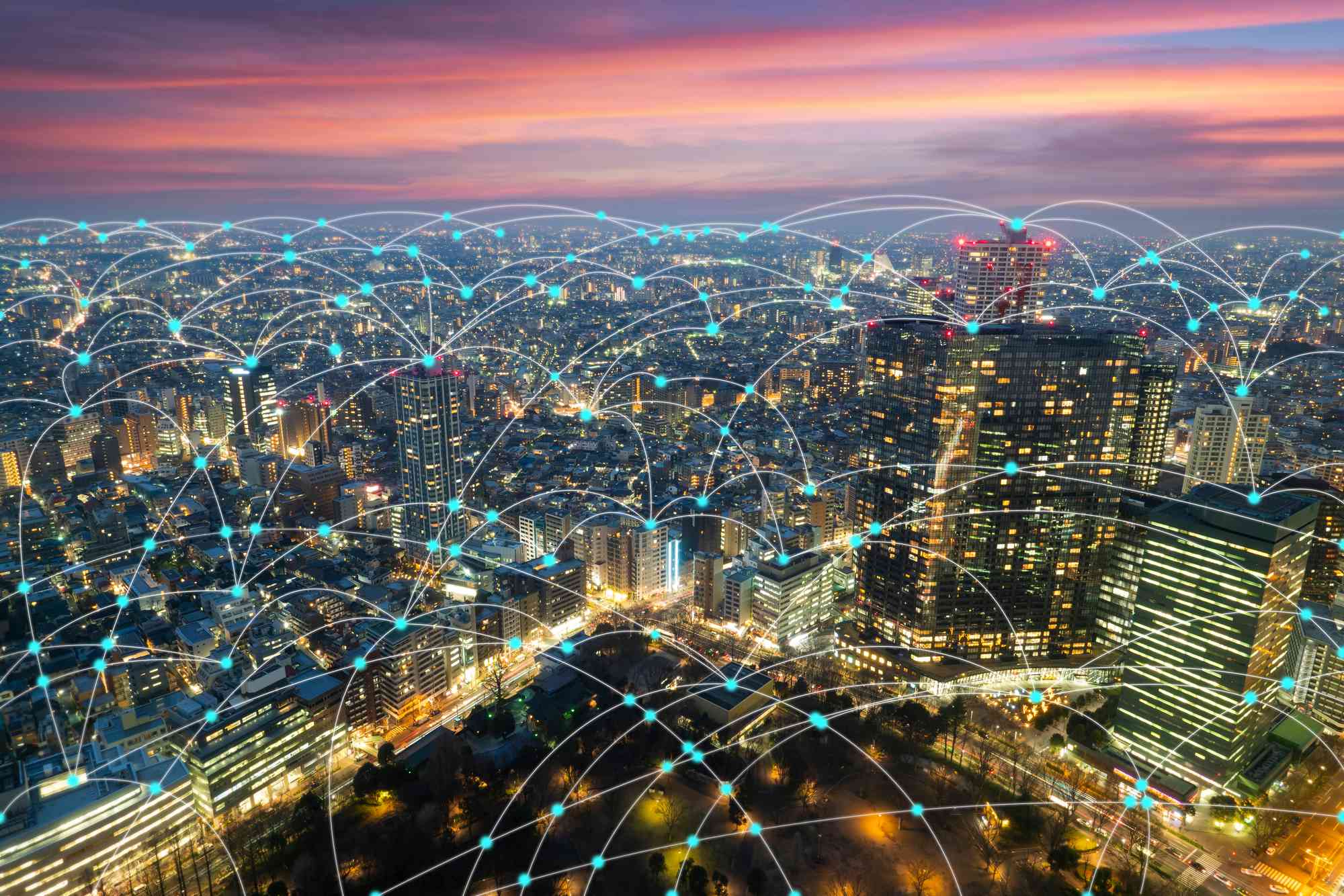 Aerial view of a vibrant cityscape at sunset, overlaid with a network of connections symbolizing urban digital connectivity.